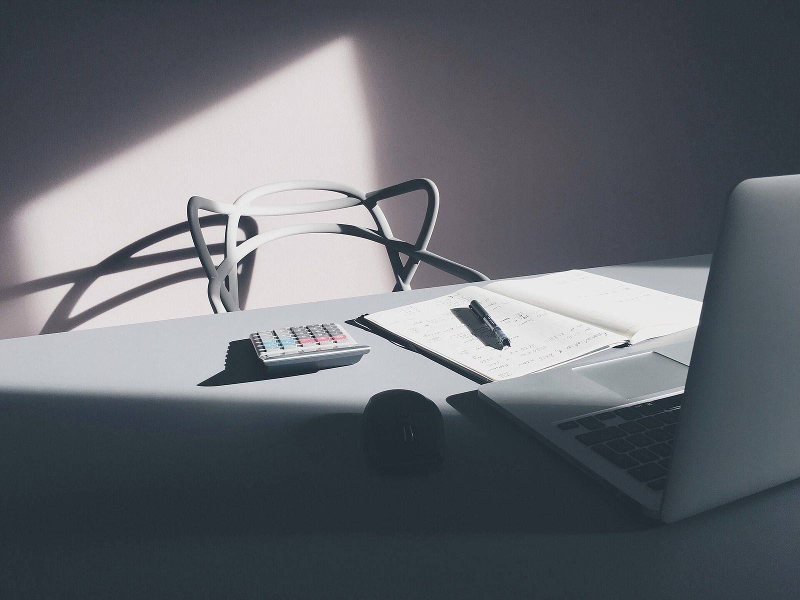 A desk with a laptop, notebook and calculator used for financial planning