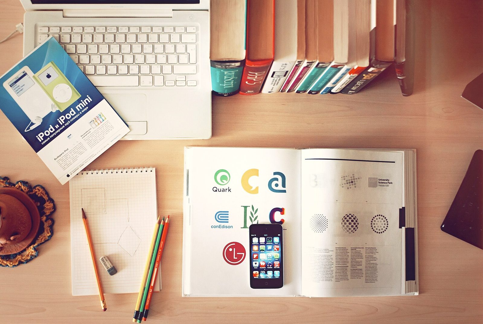 A workspace with books, pencils, a laptop and a phone laid out for planning work